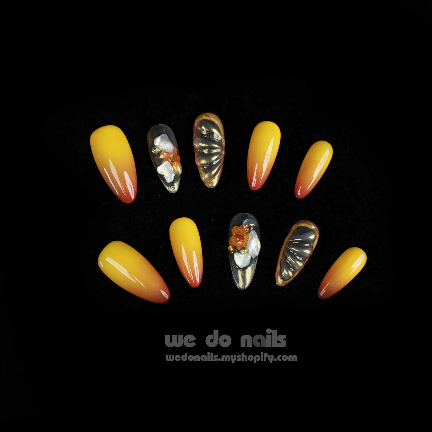 A close-up shows hands flaunting We Do Nails Sunset Glow Press-On Nails featuring long, almond-shaped manicure with bright orange, yellow, and white floral and marble patterns for a salon-quality finish. A SHIP NEXT DAY label is in the top left corner.
