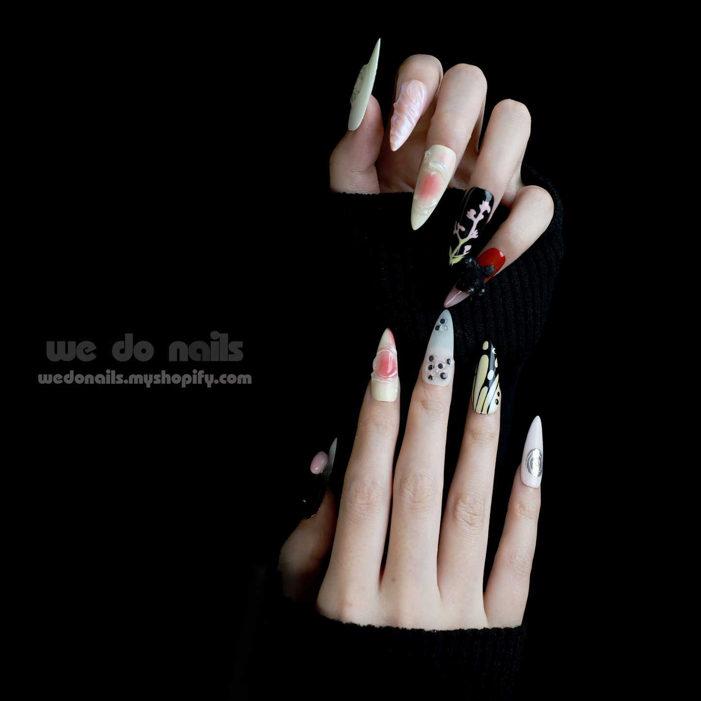 A hand holds a white mug, displaying We Do Nails Abstract Floral Design Press-On Nails, featuring intricate floral patterns in vibrant colors against a dark backdrop. Text: We Do Nails wedonails.myshopify.com.