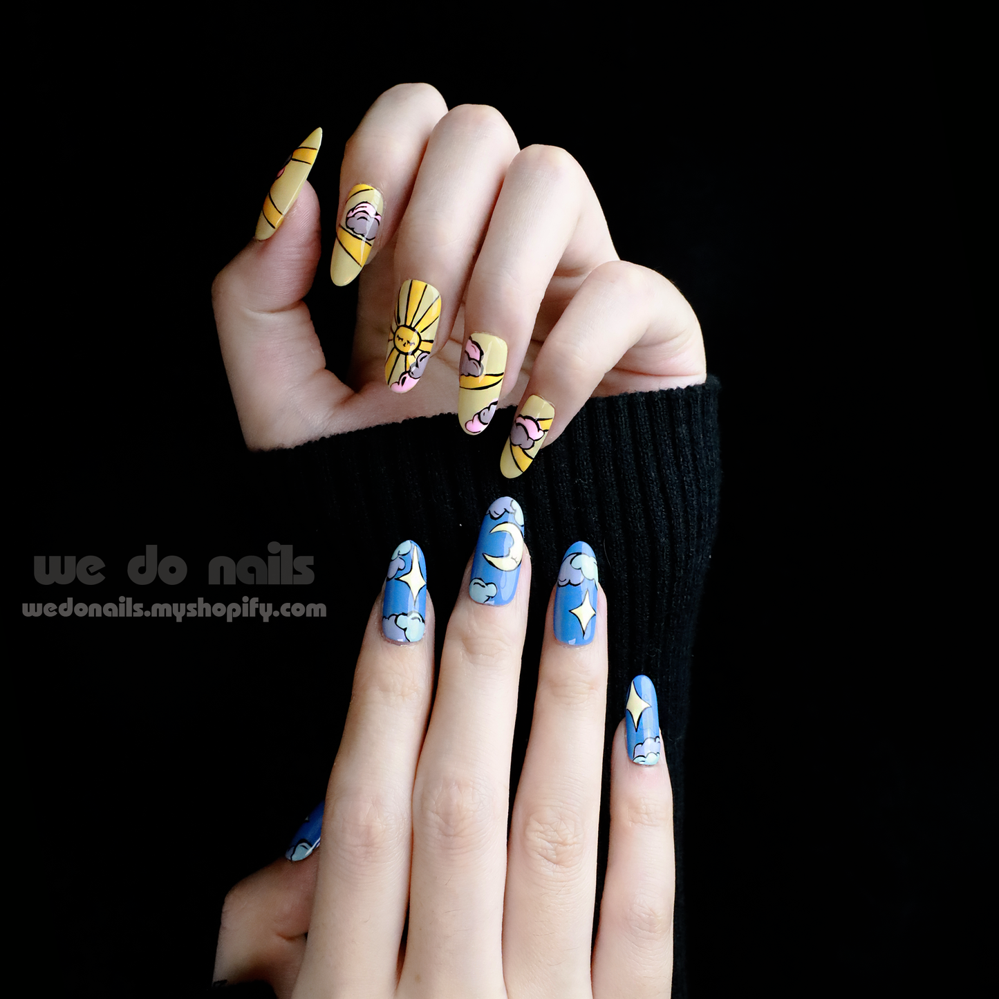 Hands with long nails display Sunrise & Moonlight Press-On Nails by We Do Nails against a black background. The top hand features sunrise-inspired yellow and pink designs with faces and stars, while the bottom showcases moonlight-inspired blue and white designs with clouds and stars.