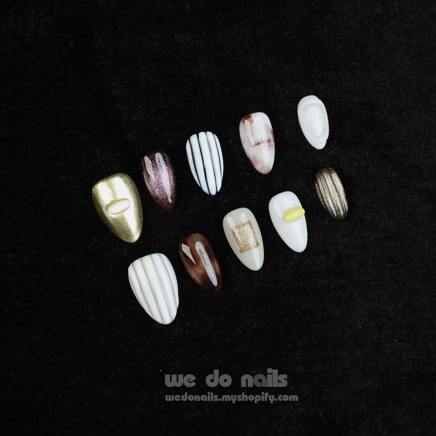 A hand with Elegant Press-On Nails holding a large white mug displays glittery stripes, marbling, and metallic textures with hints of gold. The black background has text: We Do Nails followed by the URL wedonails.myshopify.com.