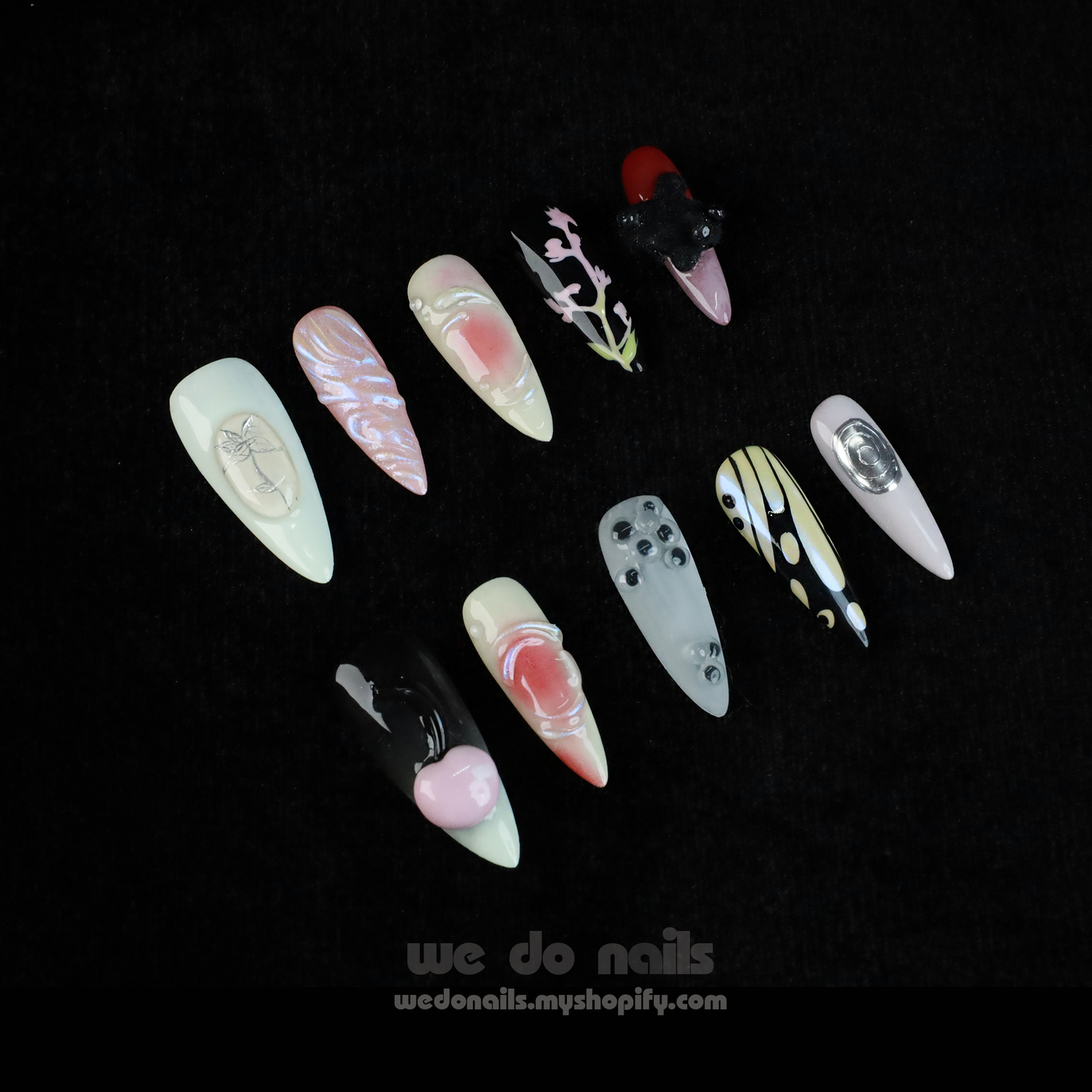 A hand holds a white mug, displaying We Do Nails Abstract Floral Design Press-On Nails, featuring intricate floral patterns in vibrant colors against a dark backdrop. Text: We Do Nails wedonails.myshopify.com.
