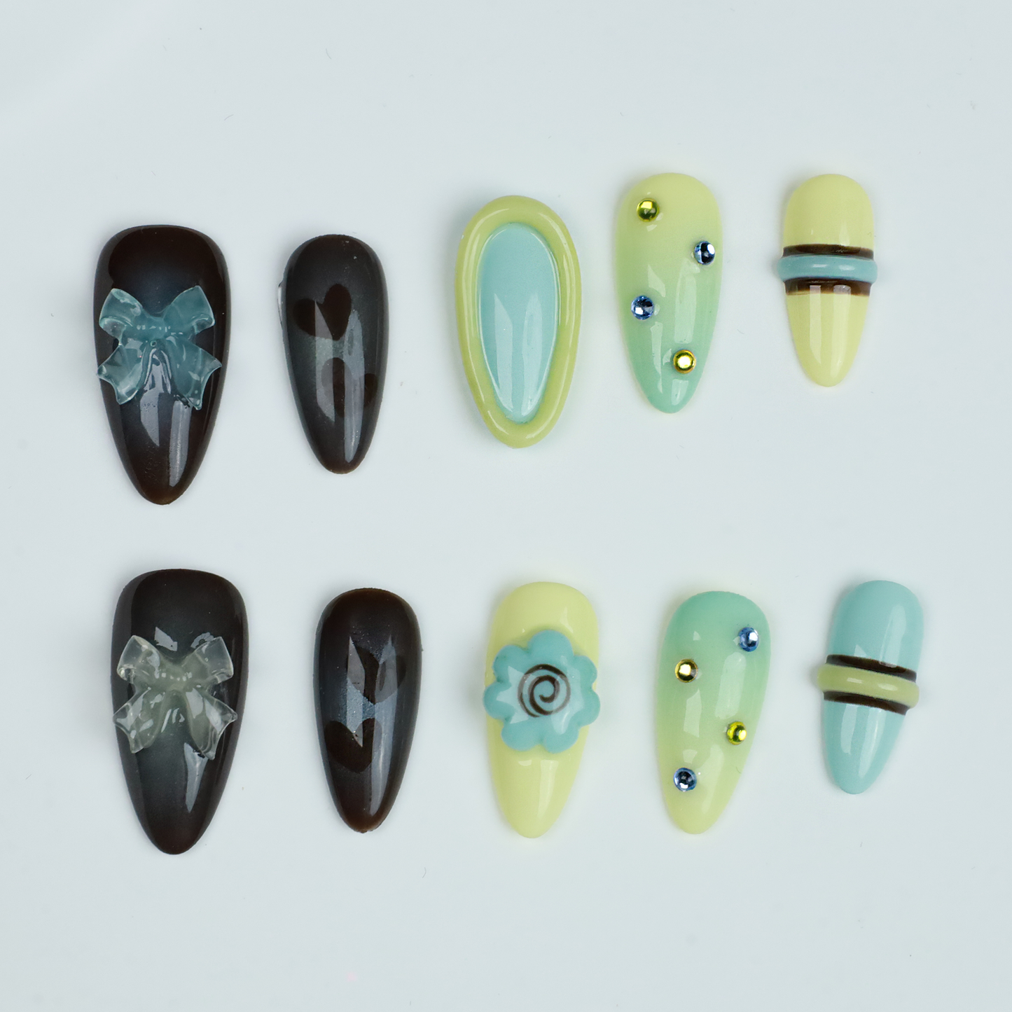 A hand showcases Elegant Edge Press-On Nails by We Do Nails from the Chic Charm Collection against a black background, with designs in brown and blue gem, camo, light yellow with stripes, pale blue with rhinestones, and yellow bordered in lime green; a sleek black sleeve adorns the wrist.