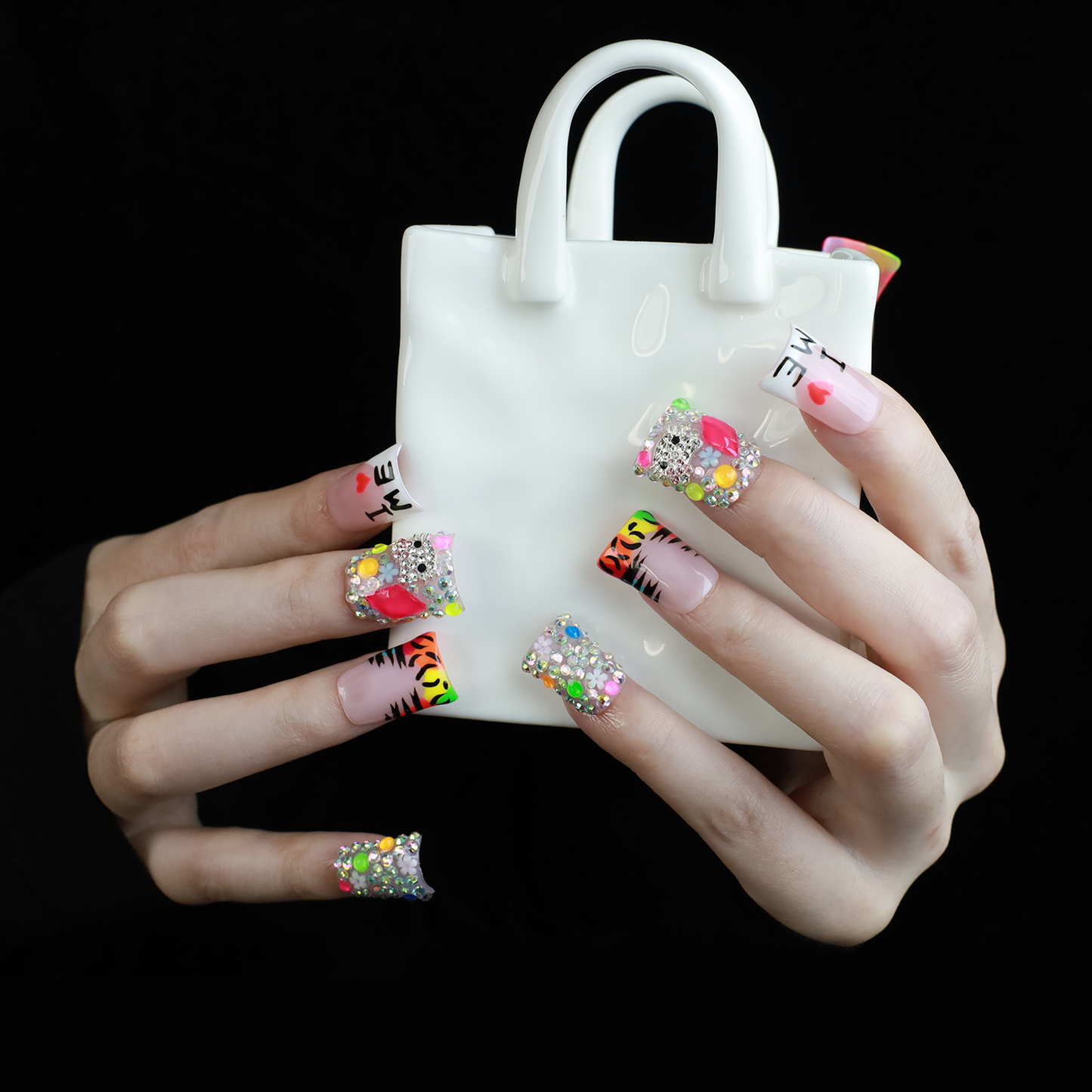 A pair of hands showcases long, decorated nails with Y2K-inspired art, including hearts and lettering. A pink banner reads SHIP NEXT DAY. The black backdrop highlights the vibrant leopard and tiger print accents on these striking Neon Safari Short Duck Press-On Nails by We Do Nails.