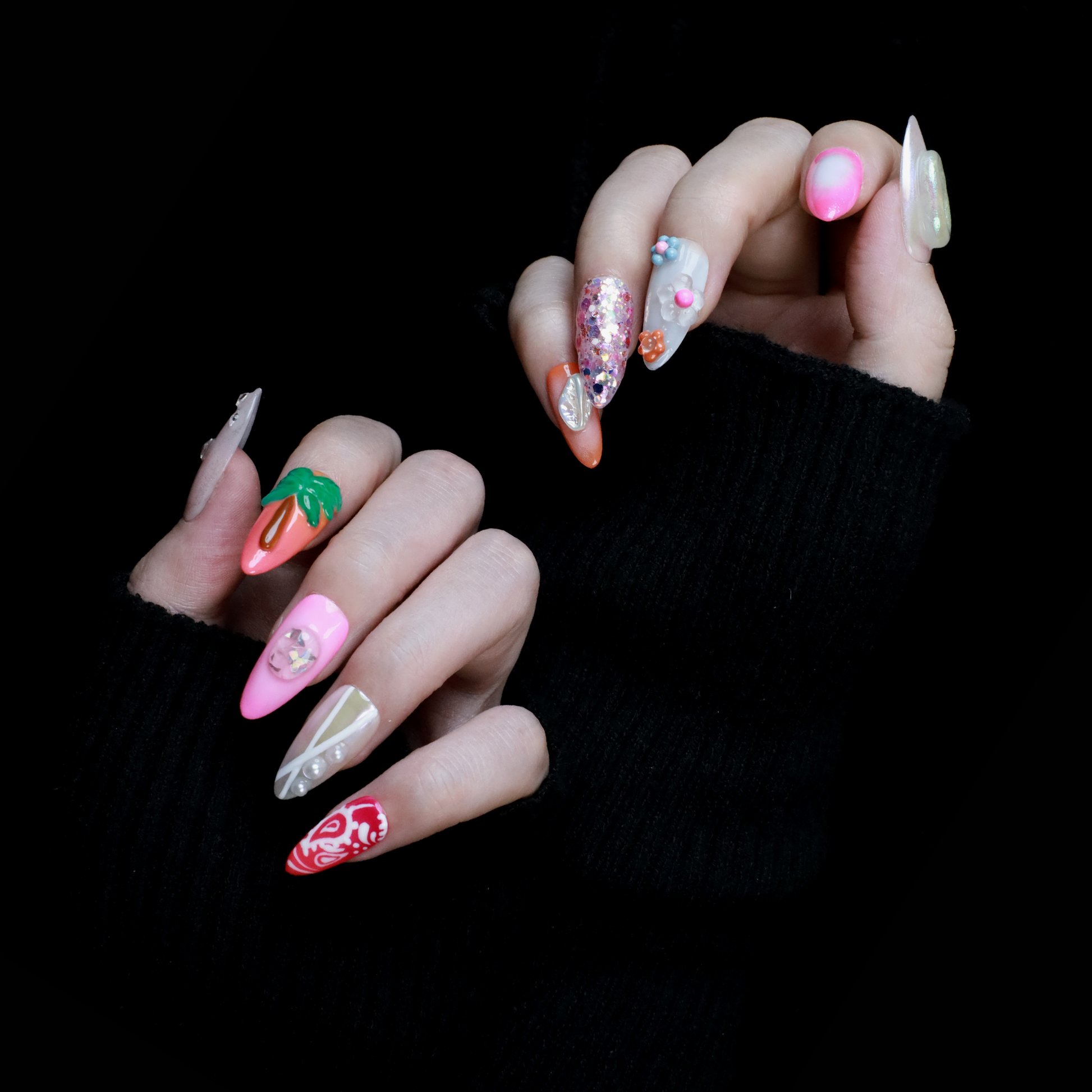 A hand features the Summer Island Press-On Nails by We Do Nails: glossy pearl-adorned, carrot-themed orange with neon, pastel pink in floral art, translucent with pearls, and red nails highlighted by an abstract white design.