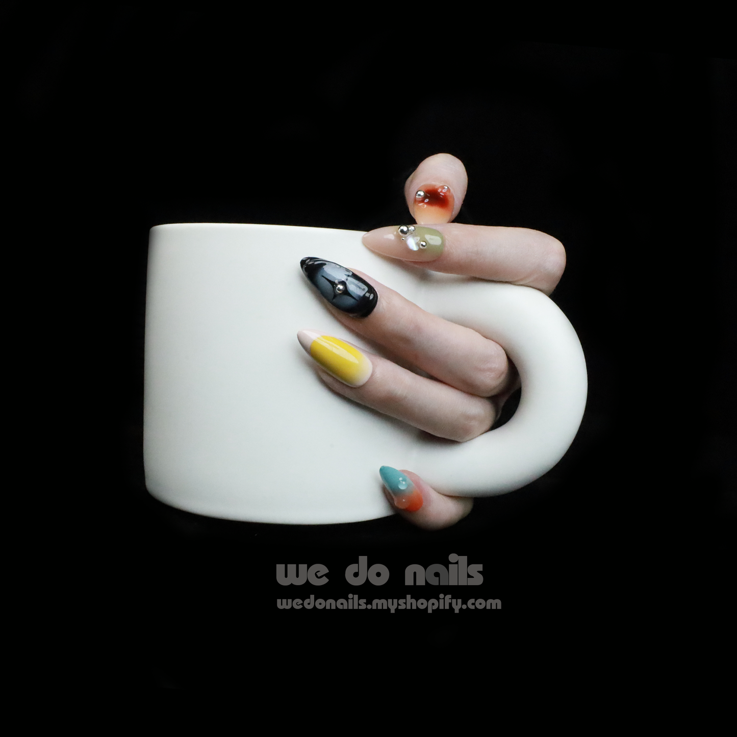 Two hands with unique, long nails showcase vibrant designs, including stripes and rhinestones, shimmering against a black backdrop. A black sleeve covers part of one hand. We Do Nails Nettle Forest Press-On Nails feature an exquisite 3D design that elevates manicures.