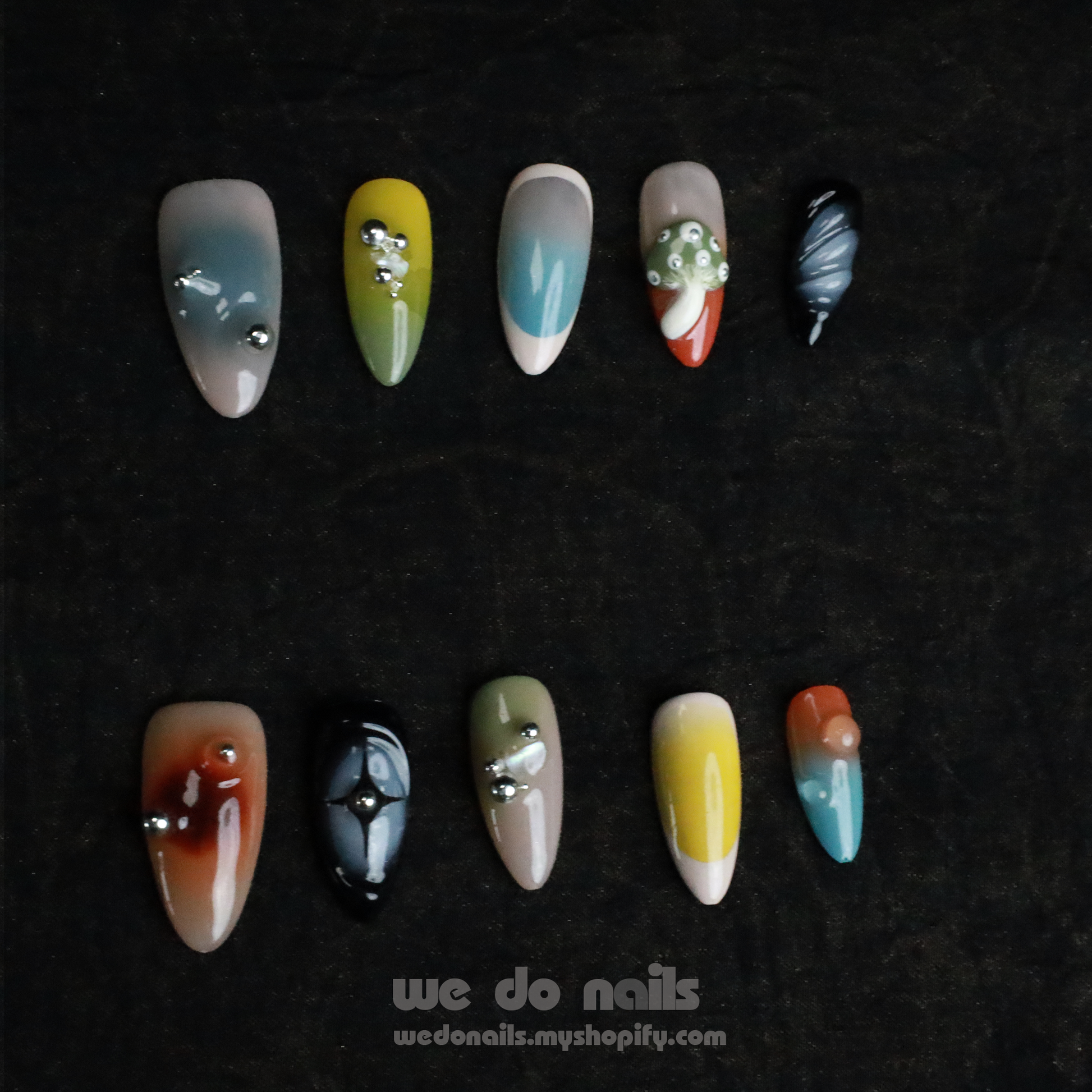 Two hands with unique, long nails showcase vibrant designs, including stripes and rhinestones, shimmering against a black backdrop. A black sleeve covers part of one hand. We Do Nails Nettle Forest Press-On Nails feature an exquisite 3D design that elevates manicures.