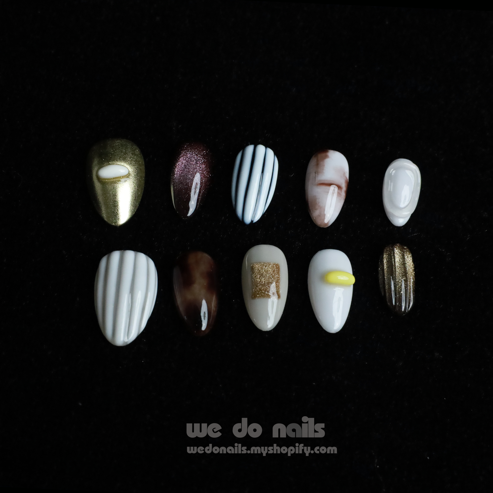 A hand with Elegant Press-On Nails holding a large white mug displays glittery stripes, marbling, and metallic textures with hints of gold. The black background has text: We Do Nails followed by the URL wedonails.myshopify.com.
