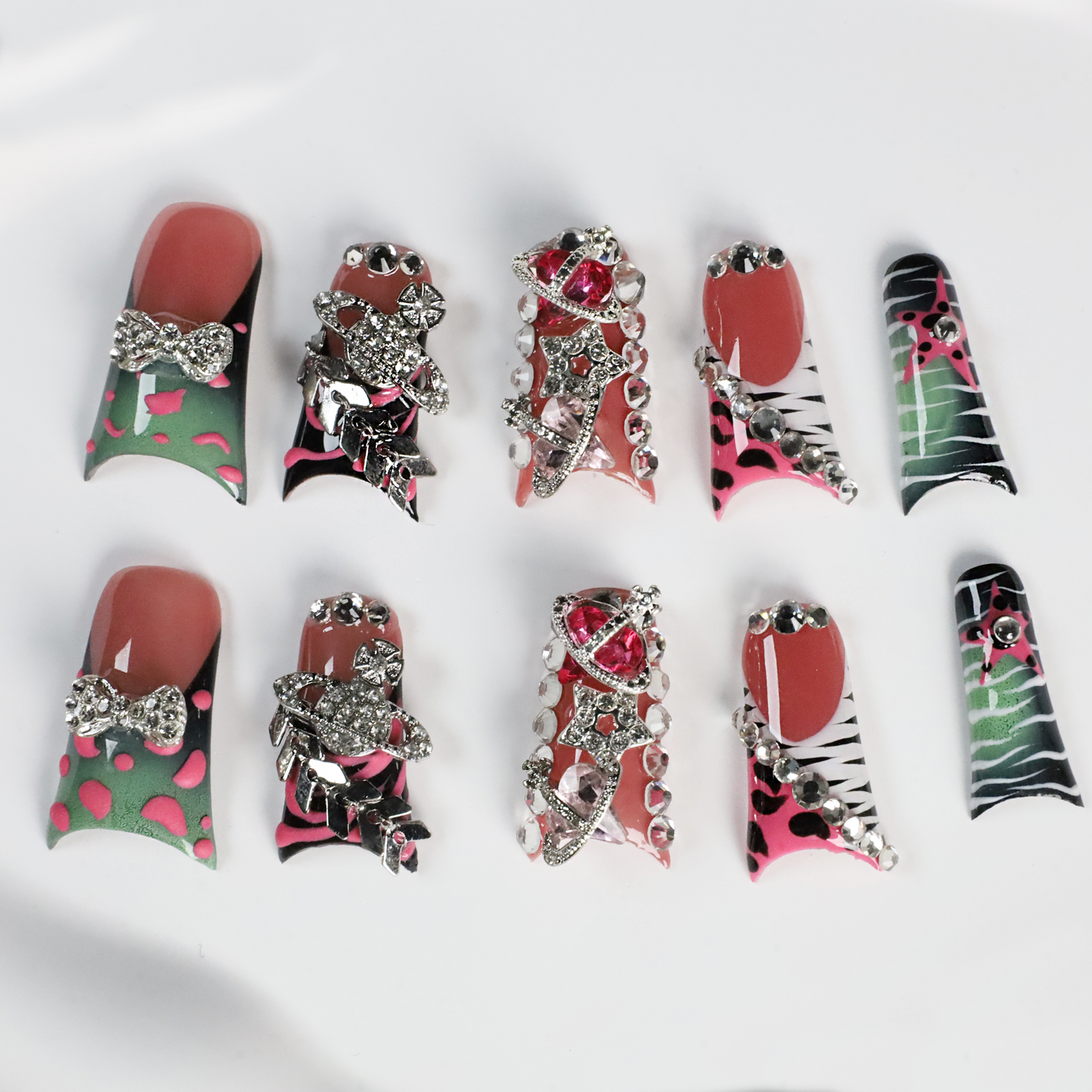 A hand displays Glam Jungle Luxe 3D Long Duck Press-On Nails by We Do Nails, featuring ornate black and red designs with rhinestone gemstones and skulls. The words SHIP NEXT DAY appear in the top-left corner, highlighting their gothic style against a dark background.
