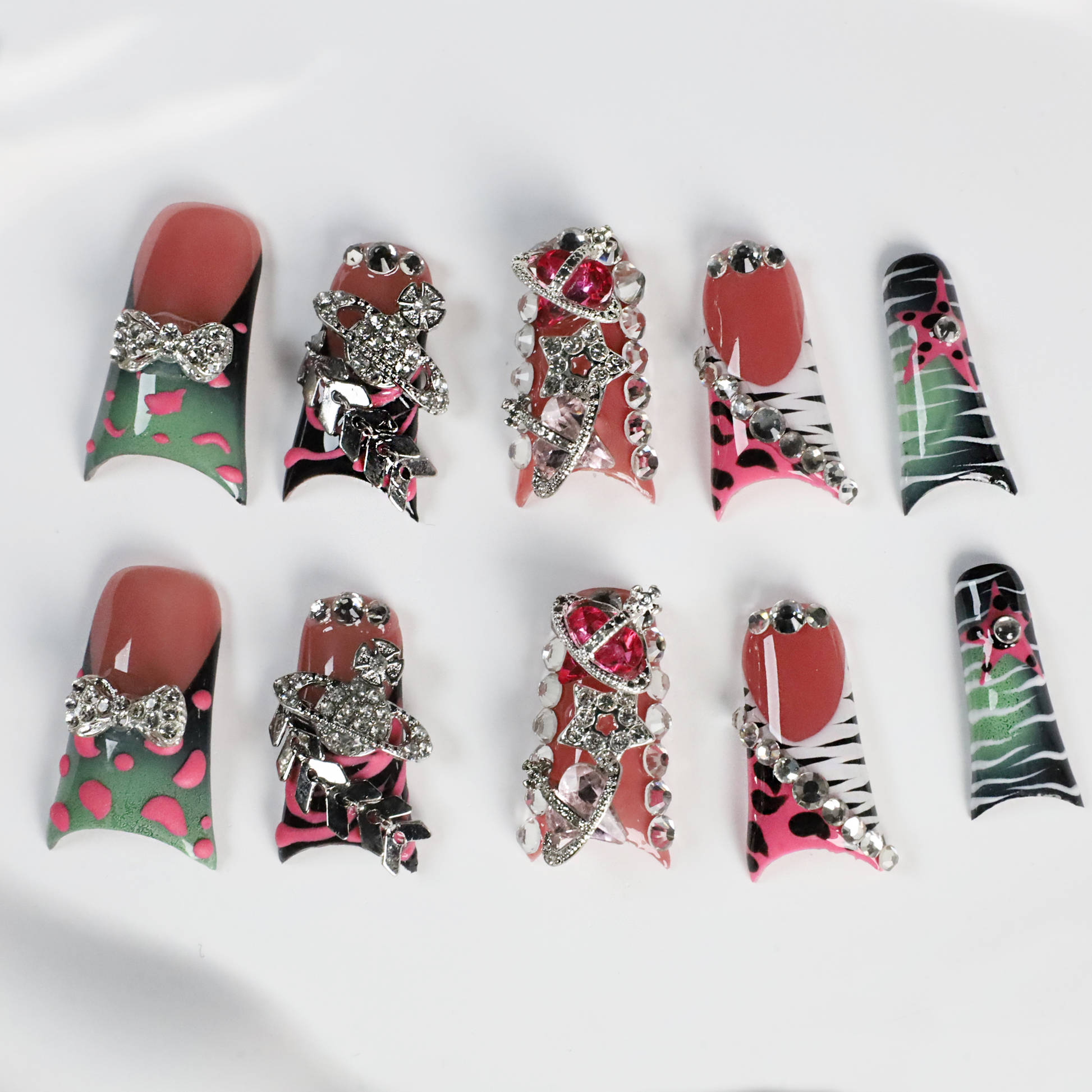 A hand displays Glam Jungle Luxe 3D Long Duck Press-On Nails by We Do Nails, featuring ornate black and red designs with rhinestone gemstones and skulls. The words SHIP NEXT DAY appear in the top-left corner, highlighting their gothic style against a dark background.