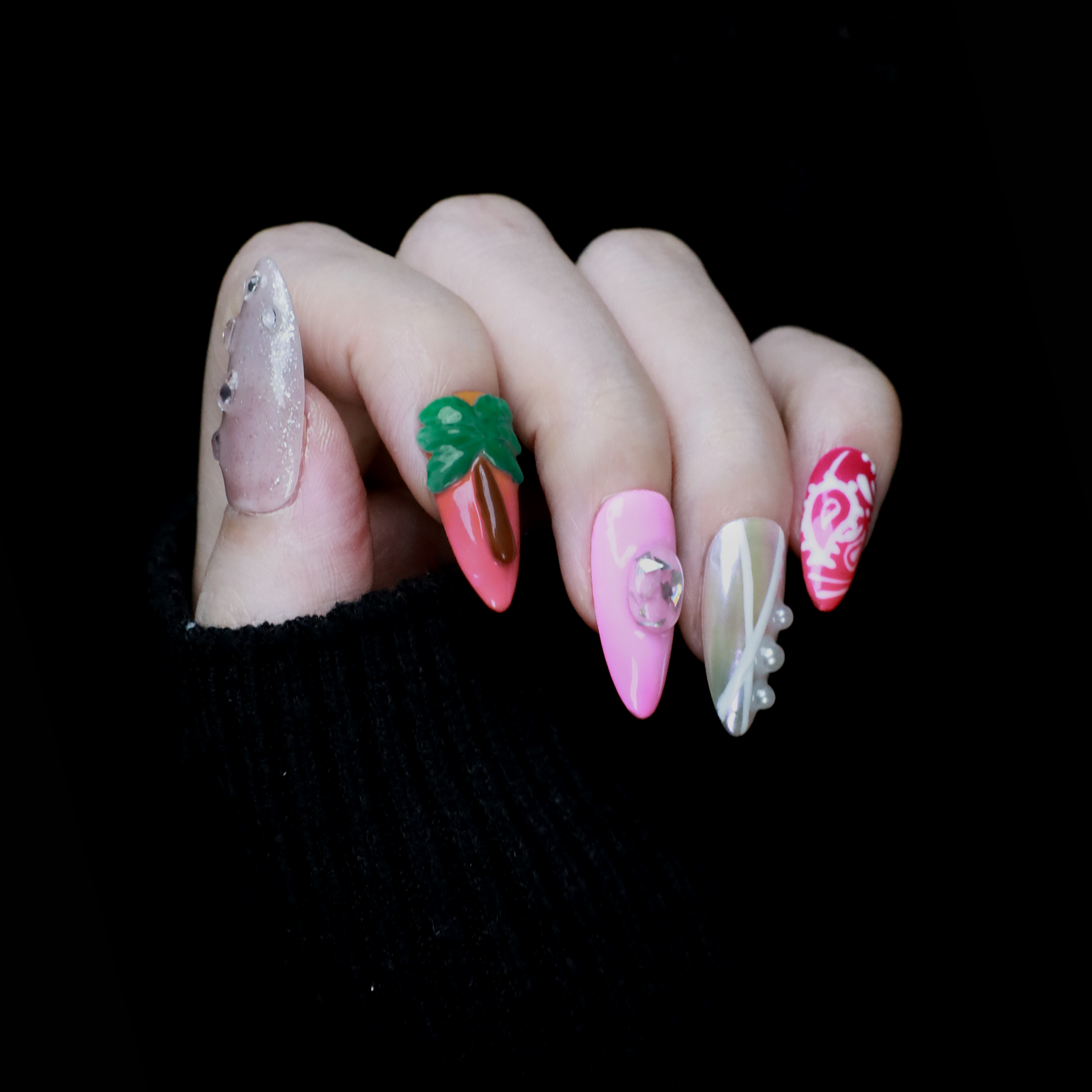 A hand features the Summer Island Press-On Nails by We Do Nails: glossy pearl-adorned, carrot-themed orange with neon, pastel pink in floral art, translucent with pearls, and red nails highlighted by an abstract white design.