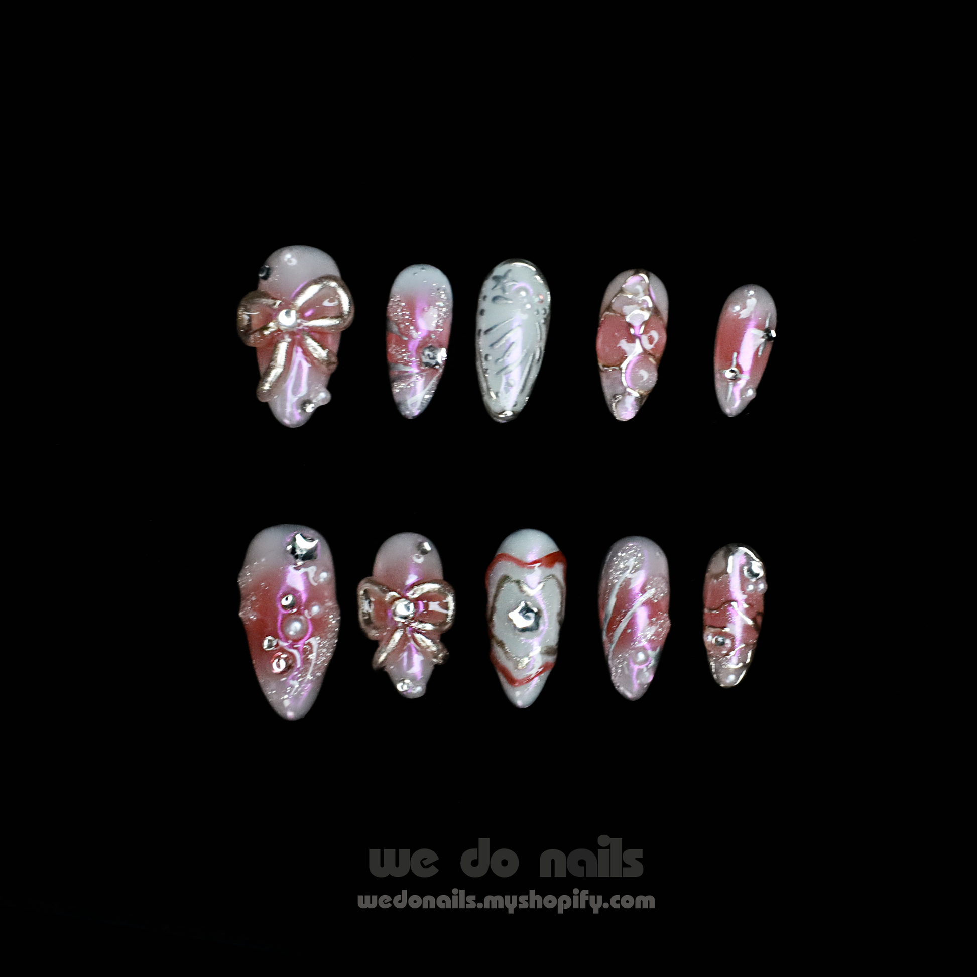 A person with intricately designed Blushing Charm Press-On Nails by We Do Nails holds a small, white ceramic handbag. The nails display soft pinks and abstract patterns in pink, white, and gold, accented with shimmering details and decorative embellishments.