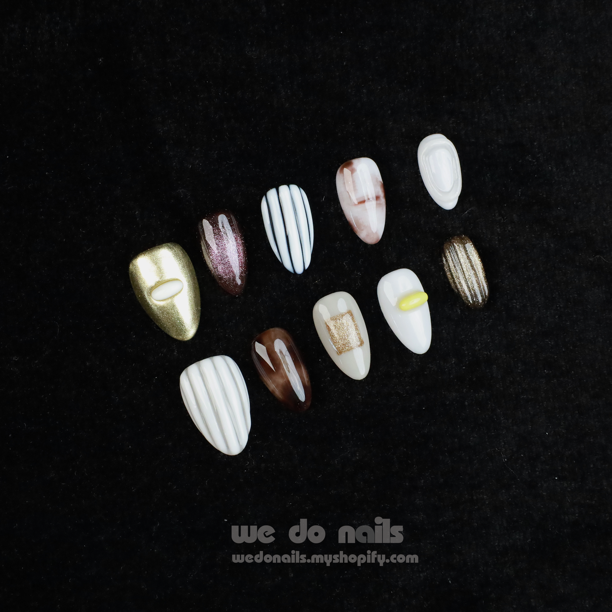A hand with Elegant Press-On Nails holding a large white mug displays glittery stripes, marbling, and metallic textures with hints of gold. The black background has text: We Do Nails followed by the URL wedonails.myshopify.com.