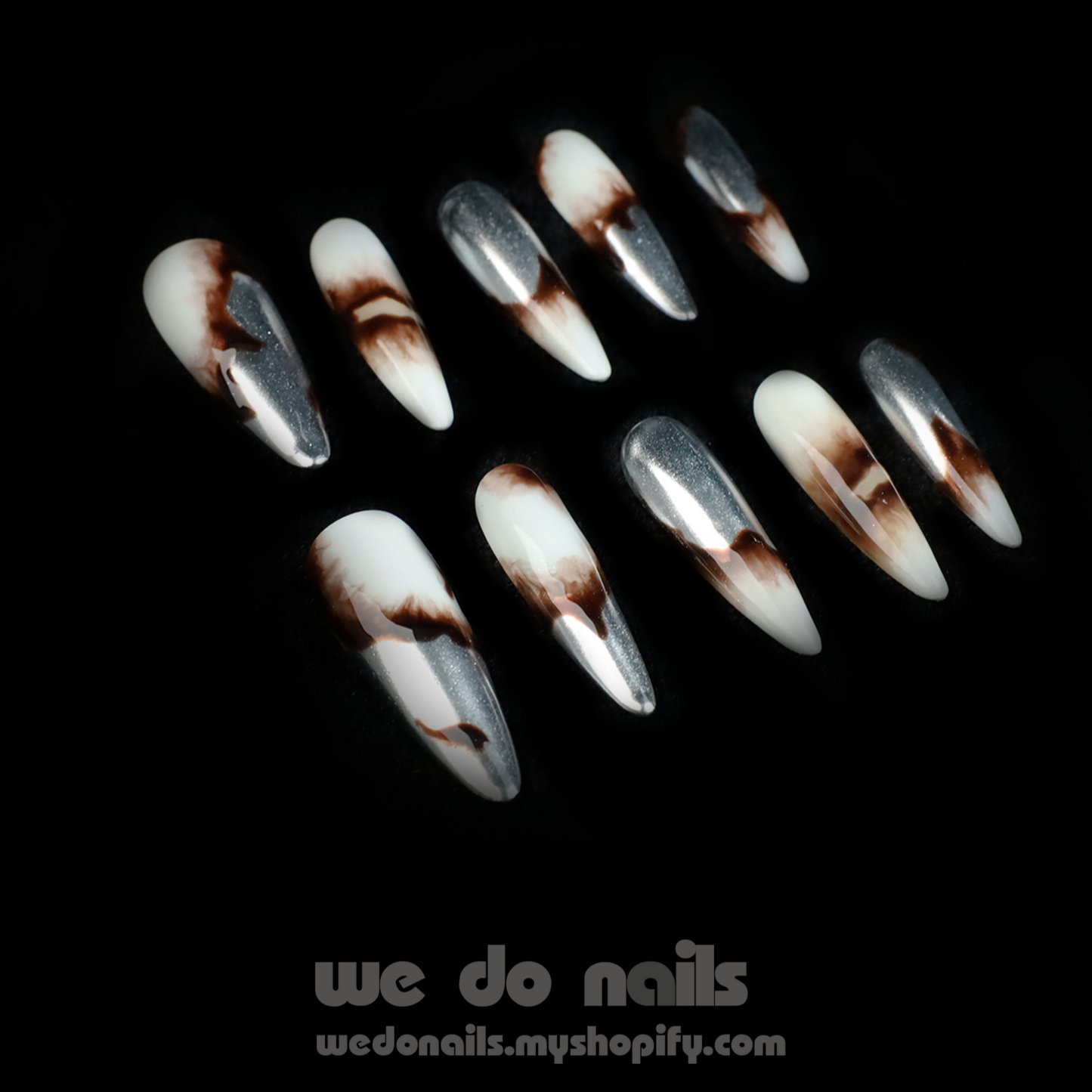 A pair of hands showcases Sizzling Marble Press-On Nails with a black and white marbled design, paired with a black long-sleeved sweater. Text includes We Do Nails and a URL. Stylish nails that redefine elegance!.