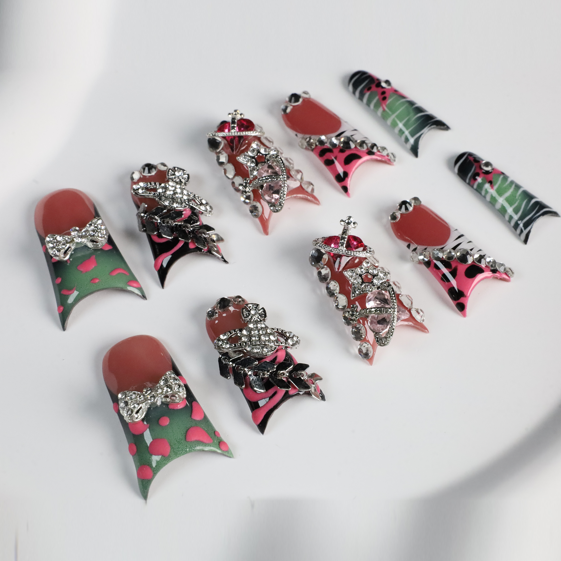 A hand displays Glam Jungle Luxe 3D Long Duck Press-On Nails by We Do Nails, featuring ornate black and red designs with rhinestone gemstones and skulls. The words SHIP NEXT DAY appear in the top-left corner, highlighting their gothic style against a dark background.