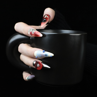 A close-up of a hand holding a black mug reveals long nails featuring vibrant, fairycore designs. The abstract patterns and bold colors create the Garden Fantasy Press-On Nails effect by We Do Nails against the dark background.