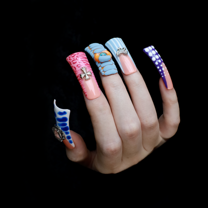Two hands showcase the Avant-Garde 3D Extra Long Duck Nails by We Do Nails, featuring blue textures, cow print, pink patterns, and colorful designs against a black background. Ship Next Day text highlights custom size and nail measurement personalization options.