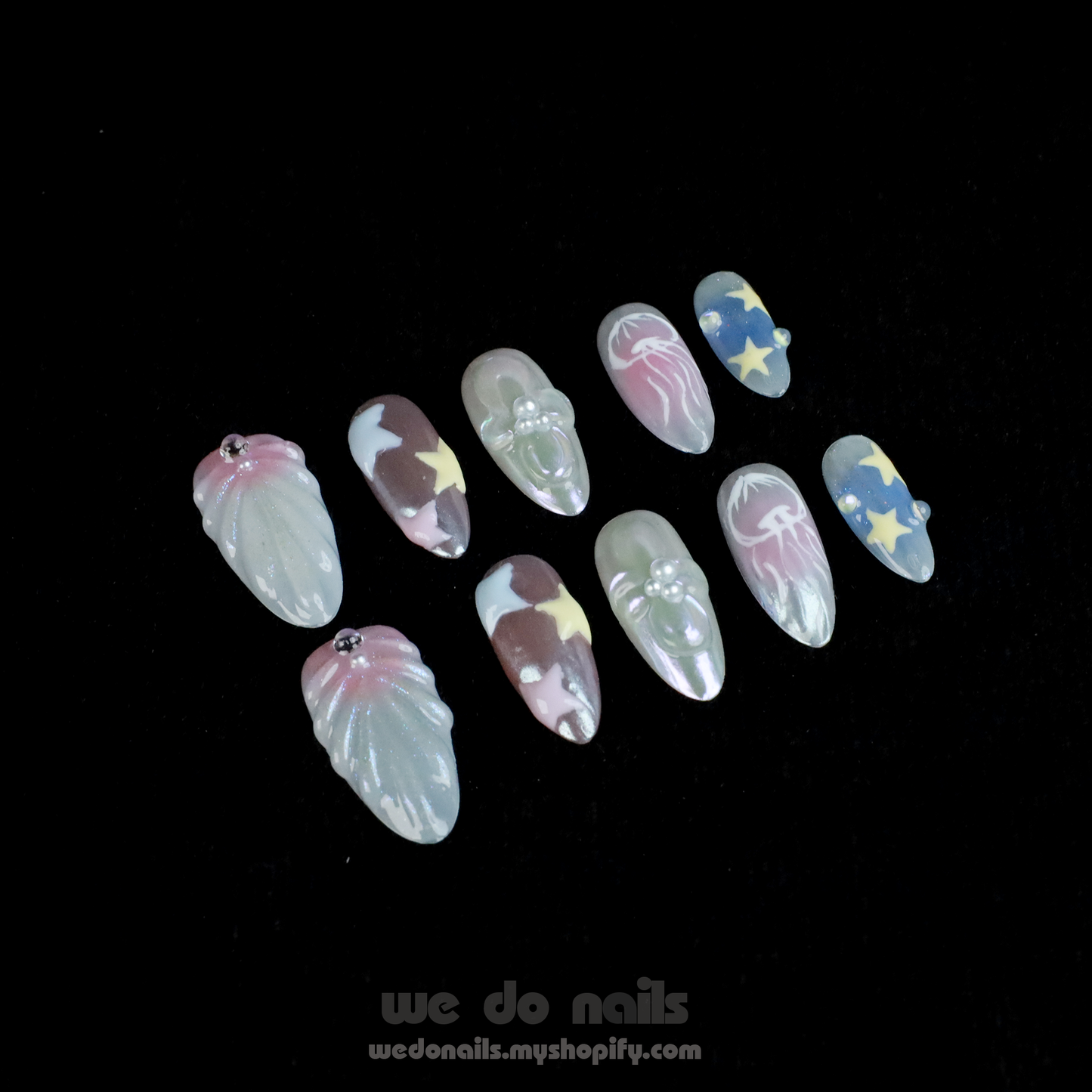 A hand with long, intricately designed Ocean-Themed Press-On Nails by We Do Nails holds a small white ceramic purse. The nails feature pastel floral and star marine motifs. A pink SHIP NEXT DAY banner appears in the top left corner.