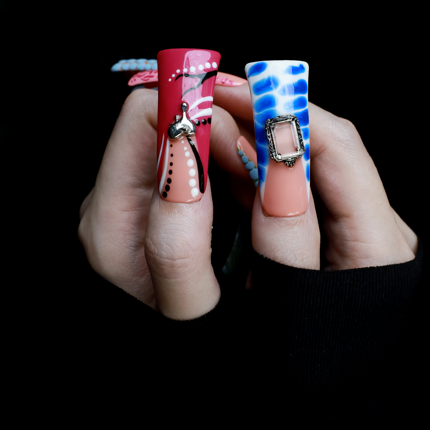 Two hands showcase the Avant-Garde 3D Extra Long Duck Nails by We Do Nails, featuring blue textures, cow print, pink patterns, and colorful designs against a black background. Ship Next Day text highlights custom size and nail measurement personalization options.