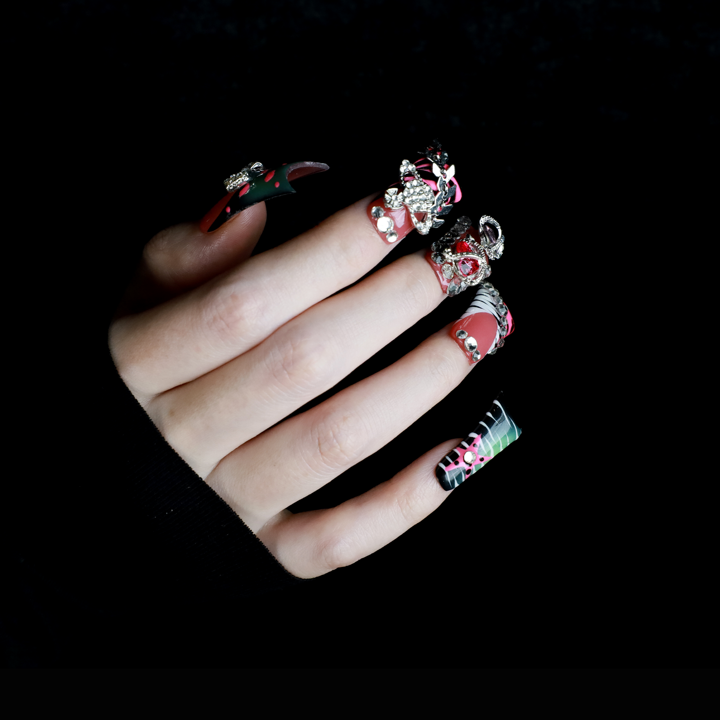 A hand displays Glam Jungle Luxe 3D Long Duck Press-On Nails by We Do Nails, featuring ornate black and red designs with rhinestone gemstones and skulls. The words SHIP NEXT DAY appear in the top-left corner, highlighting their gothic style against a dark background.