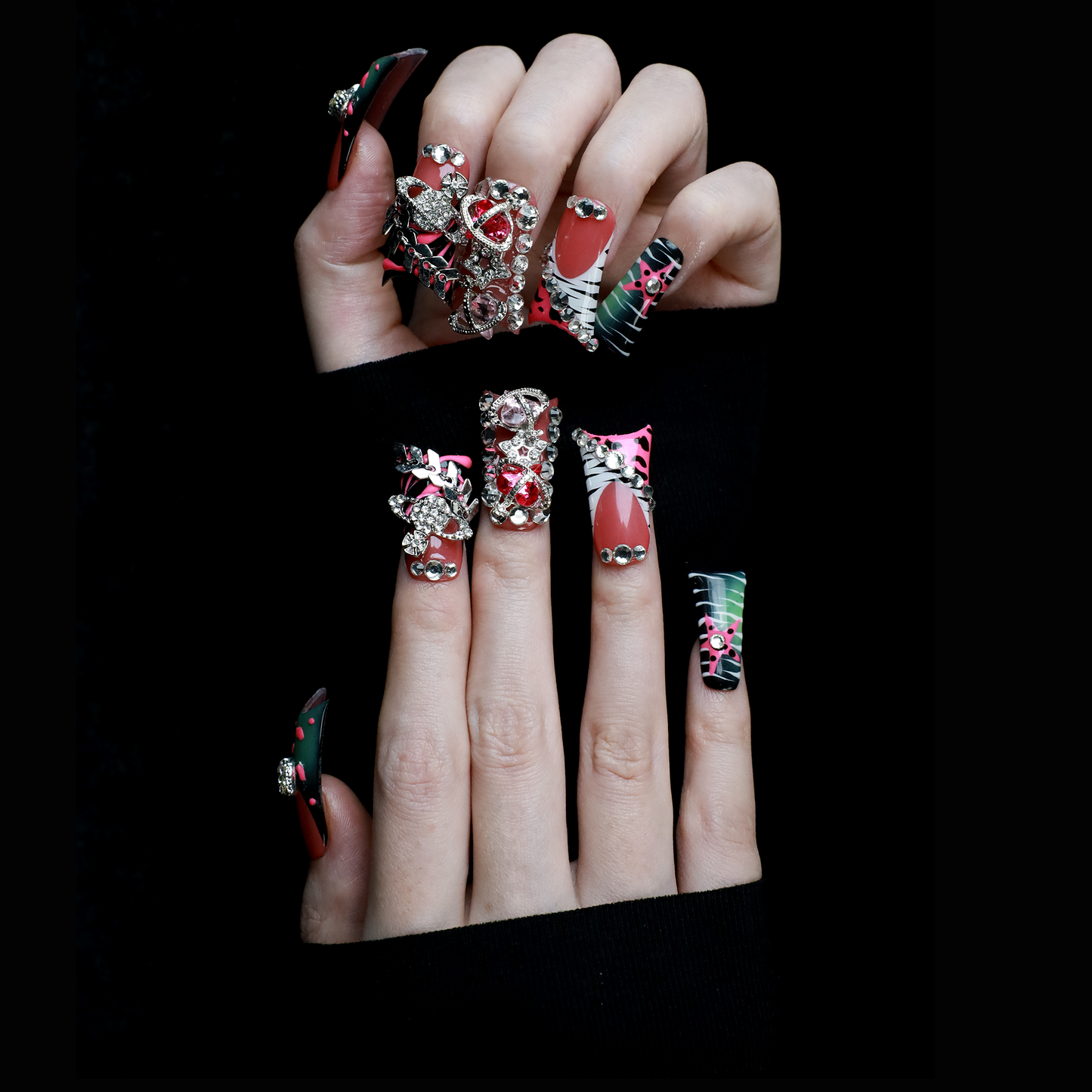 A hand displays Glam Jungle Luxe 3D Long Duck Press-On Nails by We Do Nails, featuring ornate black and red designs with rhinestone gemstones and skulls. The words SHIP NEXT DAY appear in the top-left corner, highlighting their gothic style against a dark background.
